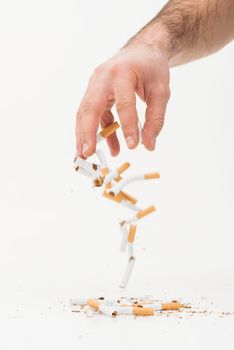 close up hand throwing broken cigarettes against white background. High resolution photo