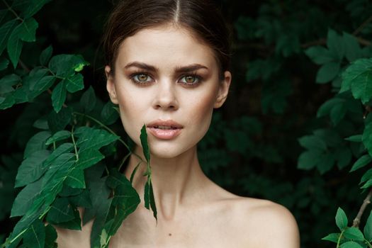 smiling woman skin care bare shoulders green leaves nature close-up. High quality photo