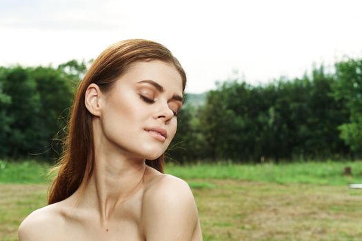 portrait of a woman in a field outdoors bare shoulders clear skin close-up. High quality photo