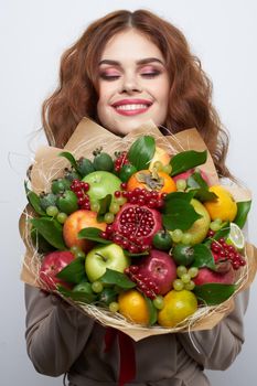 cheerful woman bright makeup attractive look a bouquet of fruits light background. High quality photo