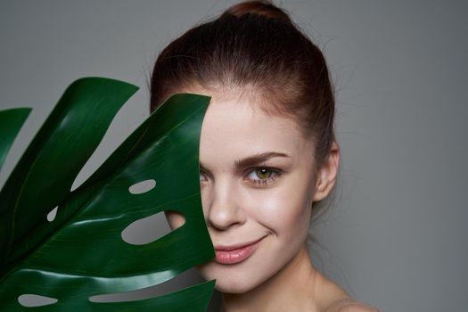 pretty woman clean skin palm leaf health cosmetics dark background. High quality photo