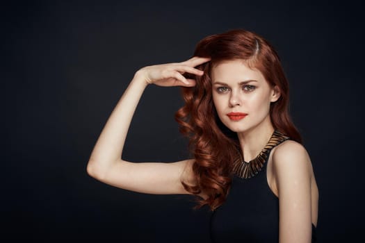attractive red-haired woman in a black dress hairstyle dark background. High quality photo