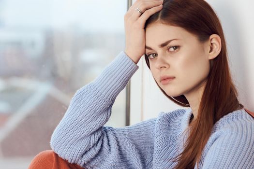 woman with sad expression sits by the window with a plaid. High quality photo