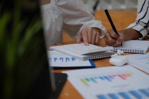 Close up Businessman and partner using calculator and laptop for calaulating finance, tax, accounting, statistics and analytic research concept