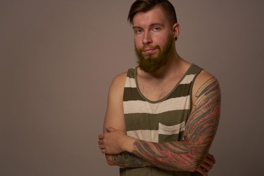 fashionable man with tattoos on his arms stylish hairstyle self-confidence studio. High quality photo