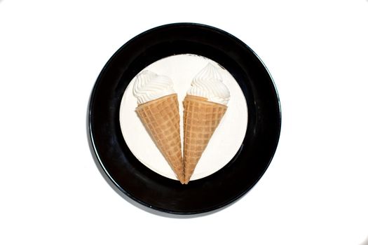 isolated round white dessert sweet delicious ice cream cake with decoration two ice cream cones in a waffle cup on a black plate. top view, close-up