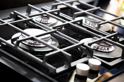 New modern black gas stove with four burners for the kitchen, stainless steel surface. Cast iron grates
