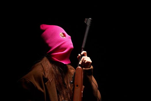 woman in glamorous pink mask shotgun posing black background. High quality photo