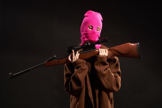 woman with gun in hand pink mask crime danger shooter. High quality photo