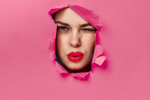 cheerful woman poster hole pink background and red lips. High quality photo