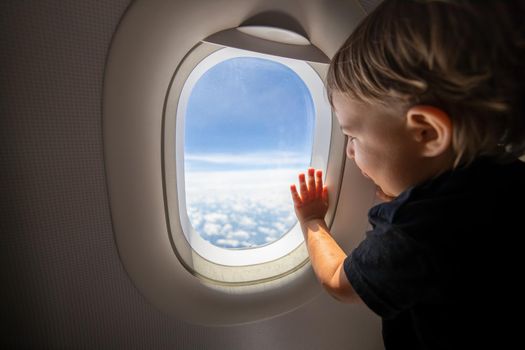 cute toddler points his finger at the sky through the window. first flight concept, traveling with children
