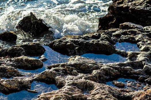 Waves crashing colorful rocks on the shore in Spain