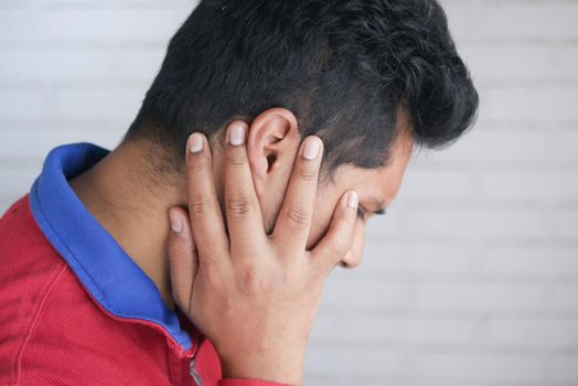 young man having ear pain touching his painful ear