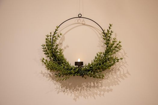 beautiful round ring Christmas candlestick wreath on a light wall.