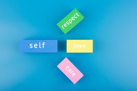 Mental health formula concept. Self respect, love and care written on multicolored rectangles on blue background. Mental health day, mental health assessment and awareness