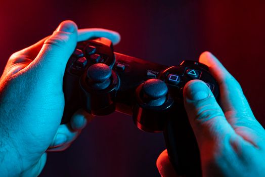 Close up of male hands playing the video game at night with joystick in hands