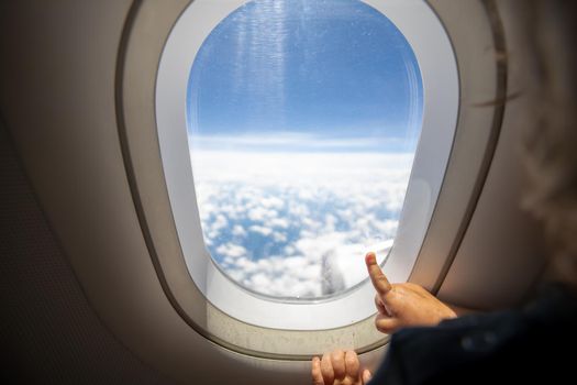 cute toddler points his finger at the sky through the window. first flight concept, traveling with children