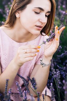 Portrait of beautiful romantic woman in fairy field of lavender with bouquet. Woman on lavender field portrait. Young woman in dress outdoors