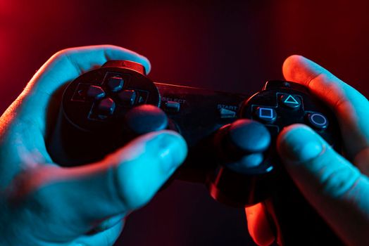 Close up of male hands playing the video game at night with joystick in hands