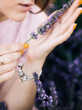 Girl hand holding beautiful lavender flowers in sunny light in meadow. Aroma herbs. Atmospheric calm rural image. Woman hand holding a bouquet of summer flowers