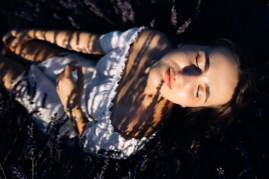 Woman is posing at field of purple lavender flowers. Beautiful woman in the lavender field on sunset in France.