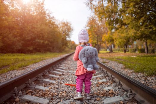 A child is walking on railway alone on a sunny summer day , dangerous act. lost child