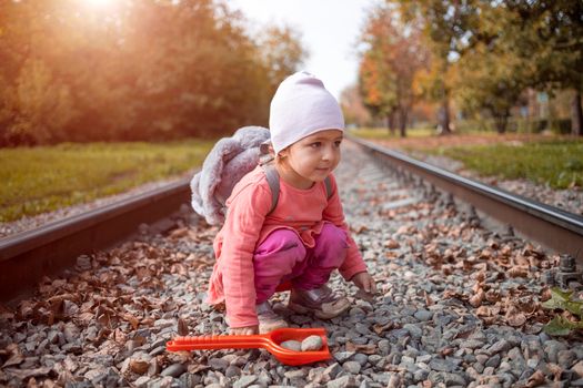 cute toddler baby girl sits on the railroad tracks alone. danger concept.