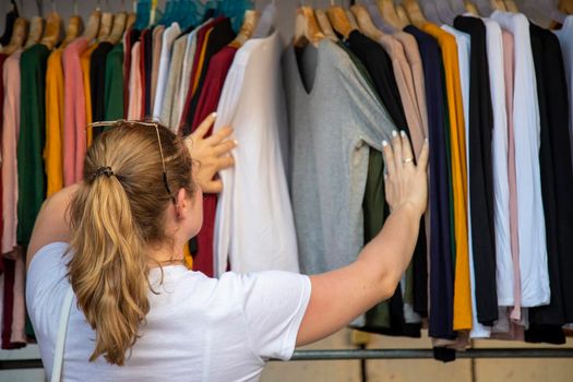 woman chooses clothes going through the broadcaster in the store at the market. rear view