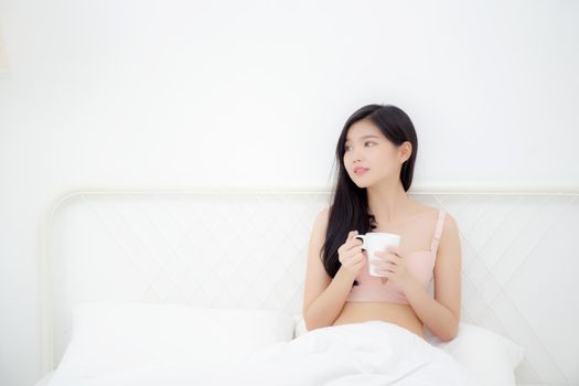 Beautiful young asian sexy woman in underwear drinking coffee in the morning on bed at bedroom, asia girl with seductive figure fit drinking beverage for relax after wake up, lifestyle concept.