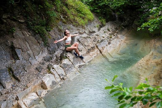 Summer travel travel. Hiking. Young happy woman enjoing the nature, sitting by the mountain river.