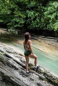Summer travel travel. Hiking. Young happy woman enjoing the nature, standing by the mountain river.