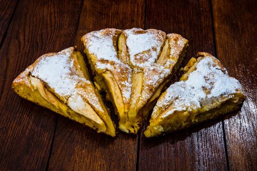 Sliced apple pie with cinnamon on rustic wooden table