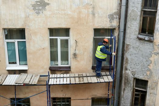 Saint Petersburg, Russia - April 24, 2021: Workers erect scaffolding to repair the facade of a building