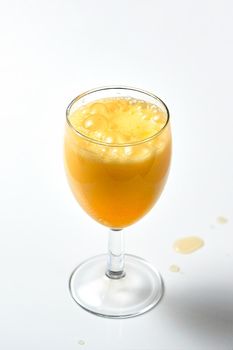 Glass goblet with bubbling orange liquid on a white background. Effervescent tablet dissolves in water