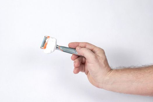 Hand holds a shaving razor with shaving foam on a white background, a template for designers. Close-up