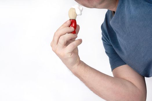 A man applies shaving foam to his face with a shaving brush. Morning or evening exercise, personal hygiene
