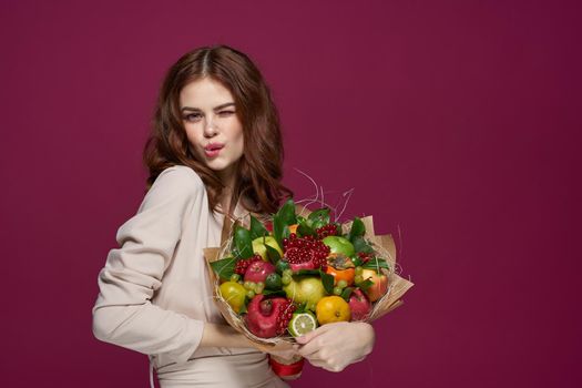 beautiful woman bright makeup attractive look a bouquet of fruits pink background. High quality photo
