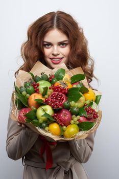 pretty woman bright makeup attractive look a bouquet of fruits light background. High quality photo