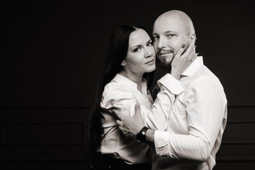 A man and a woman in white shirts on a black background.A couple in love in the studio interior.Black and white photo.