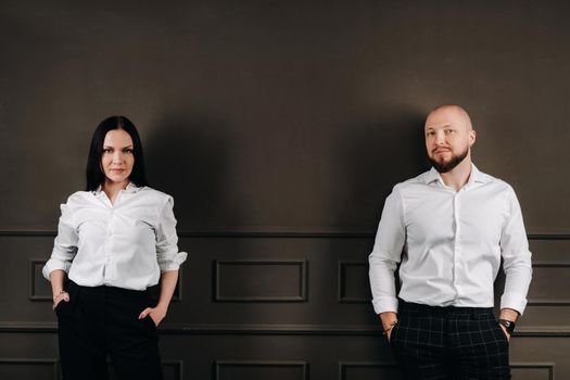 A man and a woman in white shirts on a black background.A couple in love in the studio interior.