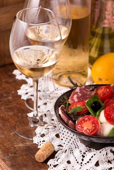 Wine and tomatoes with basil in vintage setting on wooden table