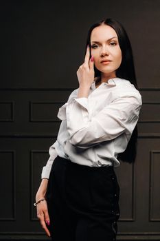Elegant brunette in a white shirt on a dark background.