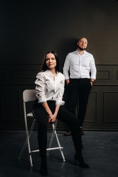 A man and a woman in white shirts on a black background.A couple in love in the studio interior.