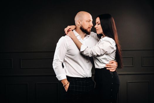 A man and a woman in white shirts on a black background.A couple in love in the studio interior.