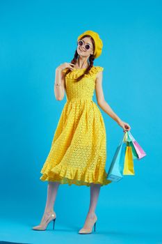 cheerful woman yellow dress shopping fun blue background. High quality photo