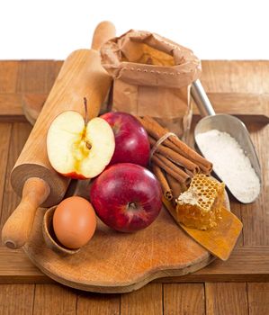 honey spoon, jar of honey, apples and cinnamon on a wooden background in a rustic style.
