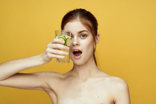 woman with cucumber drink vitamins body care yellow background. High quality photo