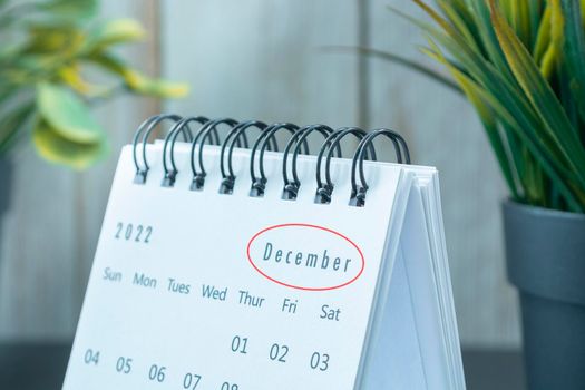 Blurred white December 2022 calendar with potted plant. 2022 New Year Concept