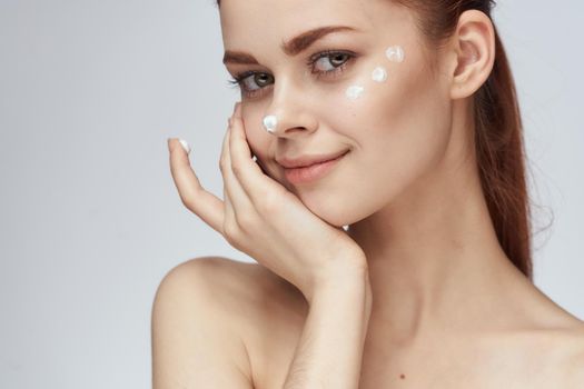 woman with face cream naked shoulders cosmetics face care. High quality photo