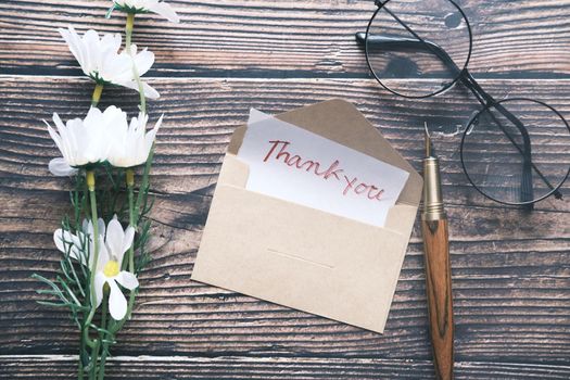 thank you message and envelope on wooden table.